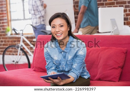 Young casual woman using digital tablet on couch in the office