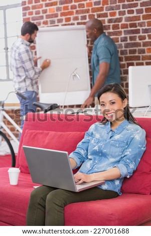 Young casual woman using laptop on couch in the office