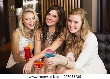 Pretty friends drinking cocktails together at the bar
