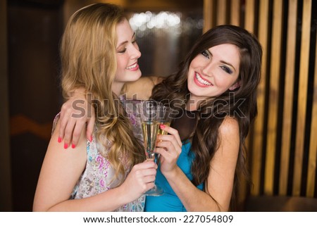 Attractive friends toasting with champagne at the bar
