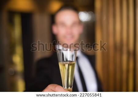 Handsome man holding flute of champagne at the bar