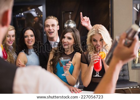 Attractive friends being served cocktails at the bar