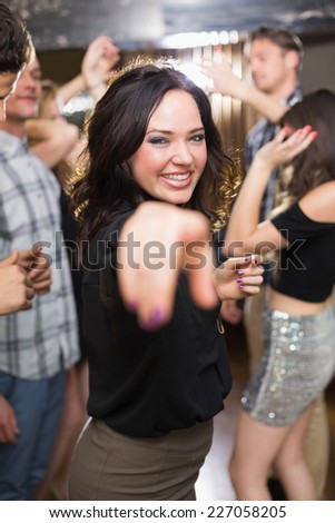 Stylish brunette smiling and dancing at the bar