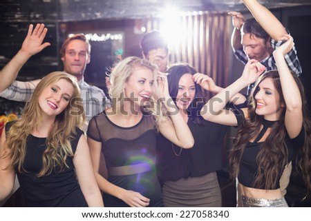 Stylish friends dancing and smiling at the bar