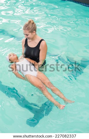 Cute little girl learning to swim with coach at the leisure center