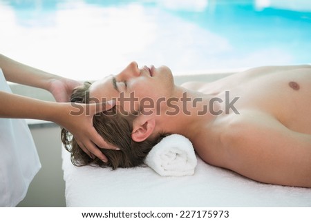 Side view of a handsome young man receiving head massage at spa center