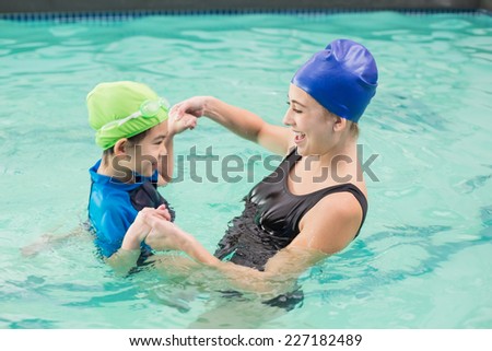 Cute little boy learning to swim with coach at the leisure center
