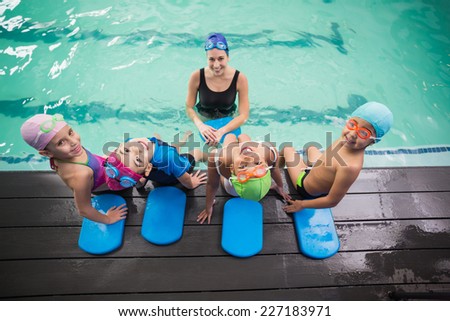Cute swimming class and coach smiling at the leisure center
