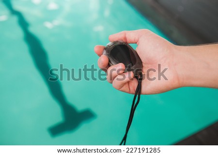 Swimming coach holding stopwatch poolside at the leisure center