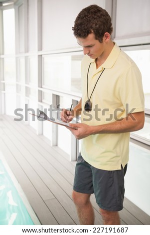 Swimming coach writing on clipboard at the leisure center