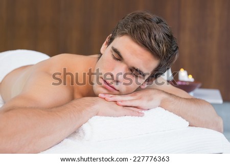 Handsome young man lying on massage table at spa center