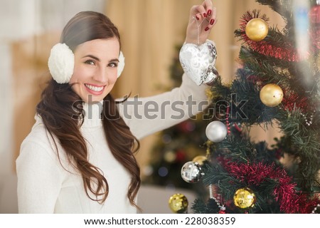 Smiling brunette holding heart near a christmas tree at home in the living room