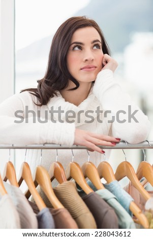 Pretty brunette looking through clothes rail at clothes store