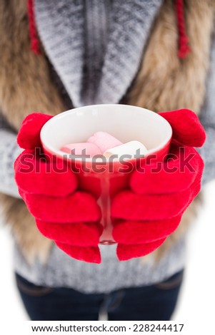 Woman in winter clothes holding a mug on white background