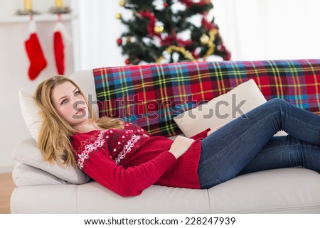 Day dreaming young woman lying on couch at home in the living room