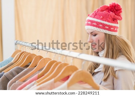 Close up of a pretty blonde looking at clothes on rail in the store