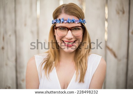 Smiling blonde woman wearing glasses and headband in front of a wooden wall