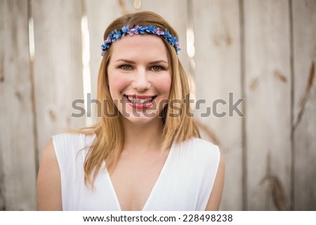 Smiling blonde woman wearing headband in front of a wooden wall