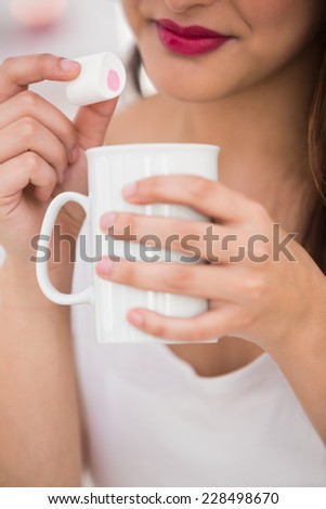 Close up of woman holding mug and marshmallow at home