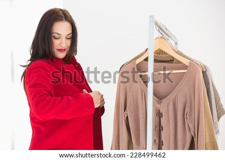 Pretty brunette trying the red coat at clothes store