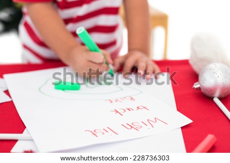 Festive little boy writing wish list on white background