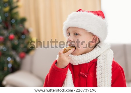 Festive little boy eating a cookie at home in the living room