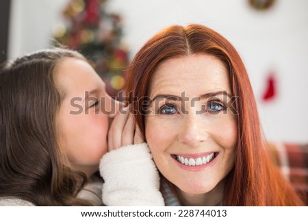 Daughter telling her mother a christmas secret at home in the living room