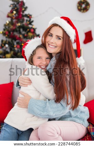 Festive mother and daughter hugging on the couch at home in the living room