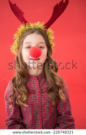 Festive little girl wearing red nose on red background