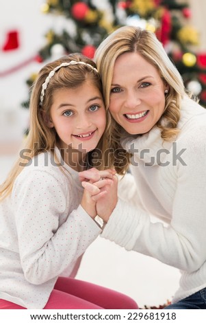 Festive mother and daughter beside christmas tree at home in the living room