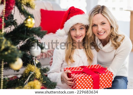 Festive mother and daughter beside christmas tree at home in the living room