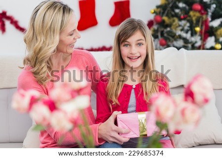 Mother giving her daughter a christmas gift at home in the living room