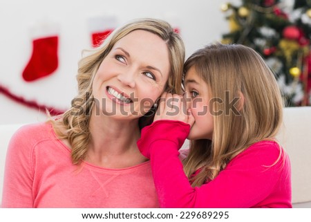 Daughter telling her mother a christmas secret at home in the living room