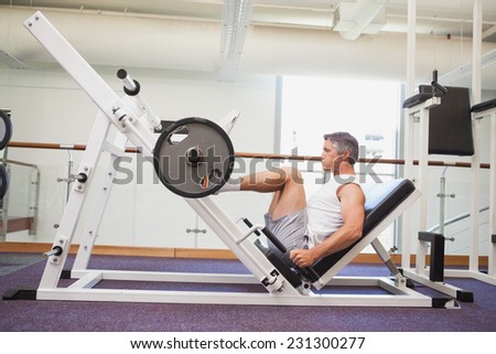 Fit man lifting heavy barbell with legs at the gym