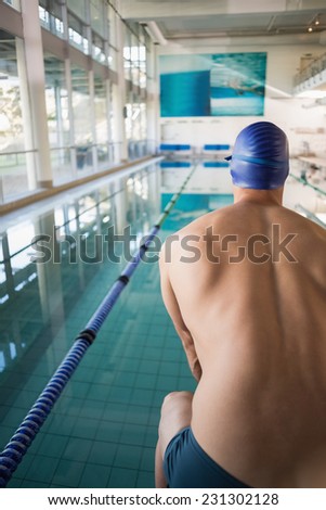 Rear view of a shirtless fit swimmer by the pool at leisure center