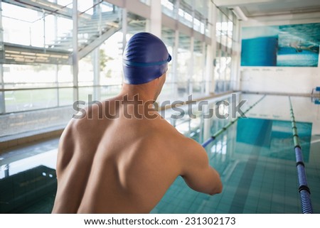 Rear view of a shirtless fit swimmer by the pool at leisure center