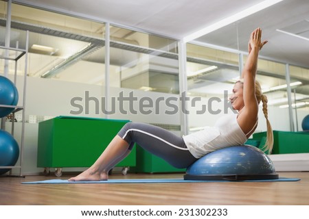 Full length side view of a young woman doing fitness exercise in fitness studio