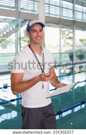 Portrait of a swimming coach with stopwatch by the pool at the leisure center