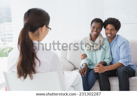 Reconciled couple smiling at their therapist in therapists office