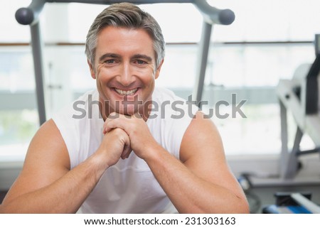 Fit man smiling at camera in fitness studio at the gym