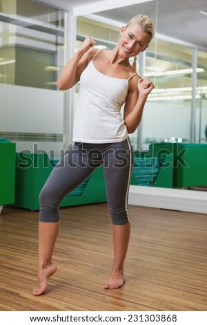 Portrait of a smiling young woman doing power fitness exercise at yoga class
