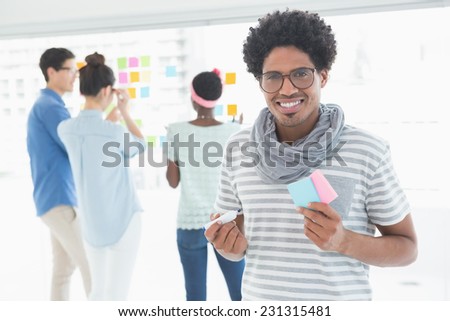 Young creative man smiling at camera in creative office