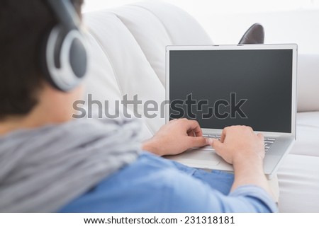 Young creative man using laptop on couch in creative office