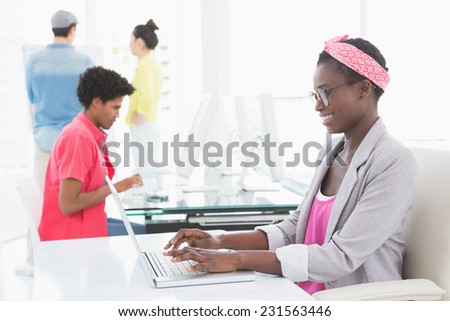 Young creative woman using laptop at desk in creative office