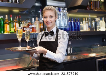 Pretty waitress holding a tray of champagne in a bar