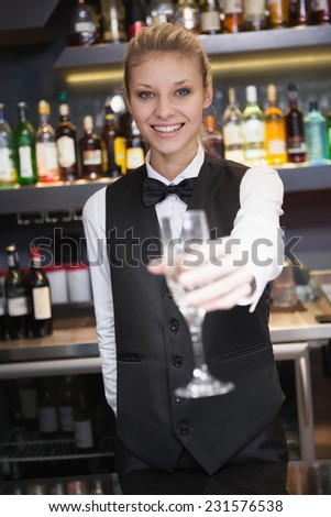 Pretty woman offering flute of champagne in a bar