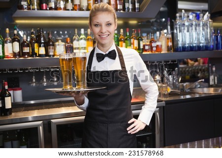 Waitress with hand on hip holding a tray of champagne in a bar