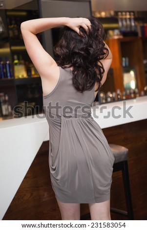 Rear view of pretty woman dancing with her hands in hair at the nightclub