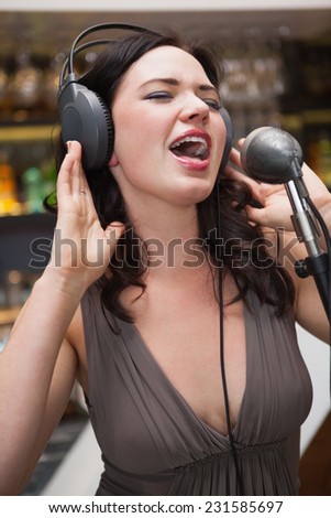 Woman singing with her hands on her headphone at the nightclub