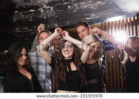 Stylish friends dancing and smiling at the nightclub